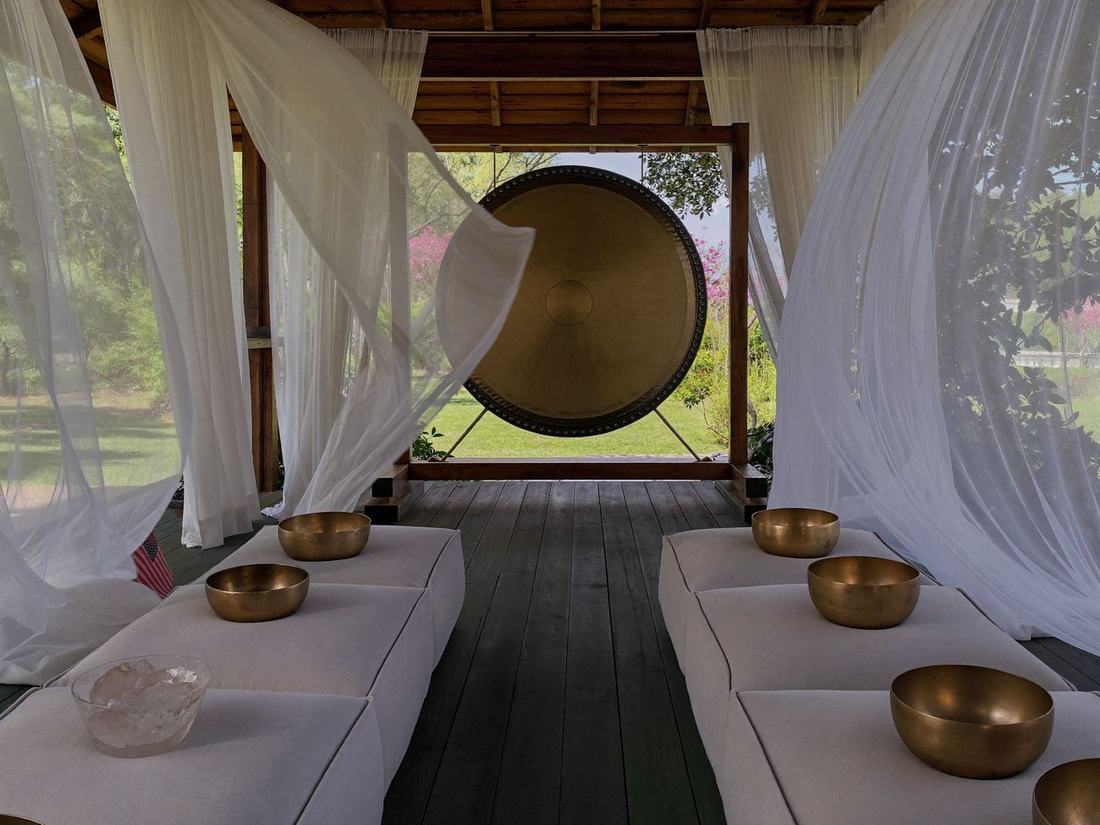 Gong und Klangschalen in einem hellen Gartenpavillon